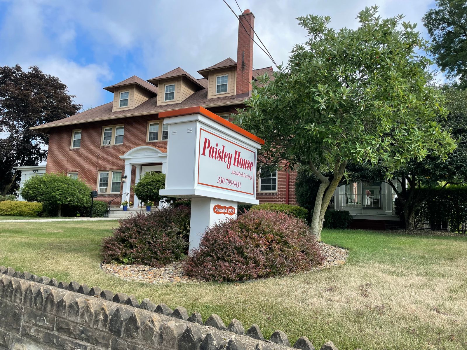 Image of the front facade of Paisley House with the sign in the yard in the fore